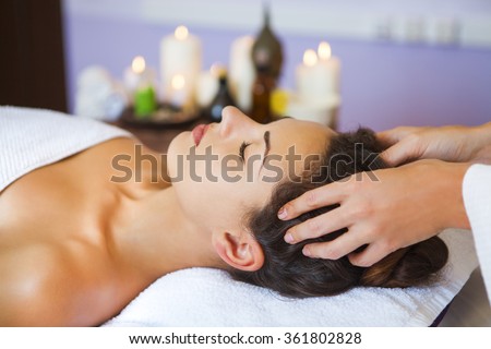 Close up portrait of a young woman getting spa treatment. Head massage
