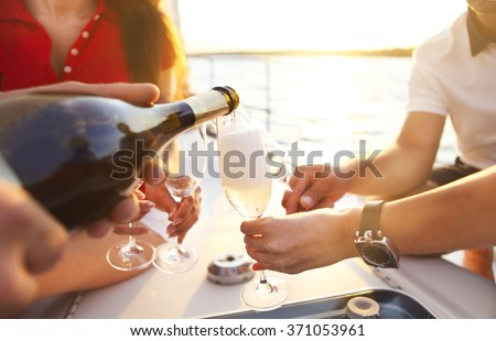 Happy friends with glasses of champagne on yacht. Vacation, travel, sea and friendship concept. Closeup.