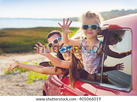 Portrait of a smiling family with two children at beach in the car.  Holiday and travel concept