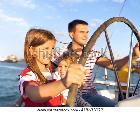 Young father with adorable daughters resting on a big boat