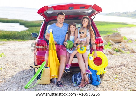 Portrait of a smiling family with two children at beach by car. Holiday and travel concept