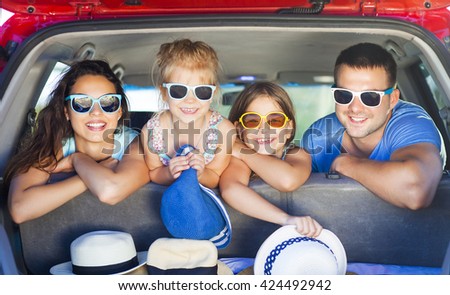 Portrait of a smiling family with two children at beach in the car. Holiday and travel concept
