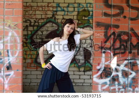 Young attractive girl brunette near the walls with graffiti