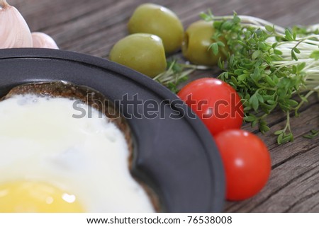Fried egg in heart-shaped form with cress, tomato, garlic, olives
