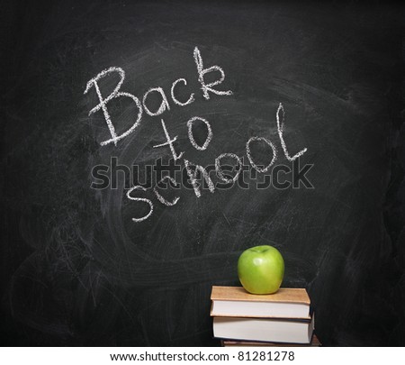 Apple on books against blackboard with text