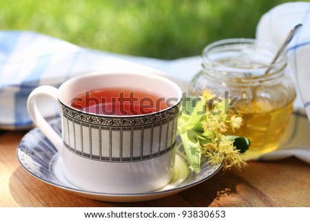 Linden honey in a jar with linden flowers and tea in the garden