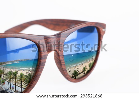Close up of colorful sunglasses on white background with beach reflection