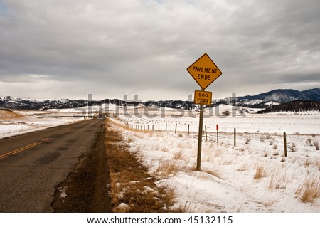 a sign indicating the end of pavement on a rural road in the mountains of Montana