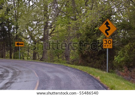 signs indicating a winding road and arrow indicating a sharp curve on a secondary road in the foothills of the Ozark Mountains