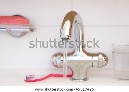 faucet in bathroom with toothbrush and soap