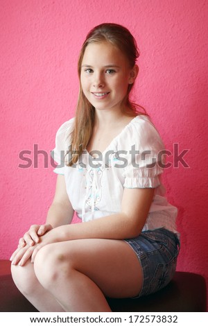 A beautiful blond-haired 13-years old girl, portrait over pink background