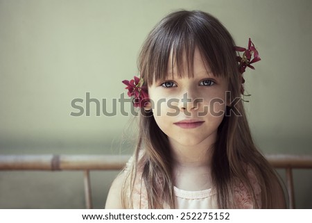 Portrait of a cute little girl with long hair and flowers in her hair