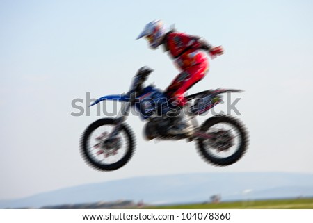 freestyle motocross rider jumps through the air, blurred motion