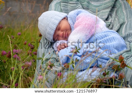 newborn baby boy in knitted jacket asleep at the garden