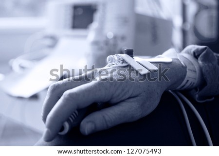 Close up of a patient hand with needle for intravenous dropper in hospital, monochromatic