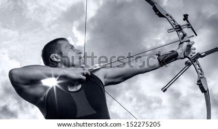 Tough man with bow and arrows, close up with cloudy sky at background. Monochromatic
