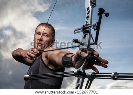 Tough man with bow and arrows, close up with cloudy sky at background