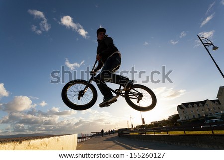 Young man performs  stunts during sunset at the street.