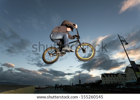 Young man performs stunts during sunset at the street.