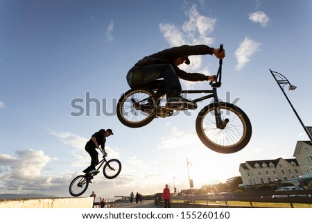 Two Young men performs  stunts during sunset at the street.