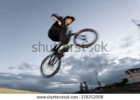 Young man performs BMX stunts during sunset at the street. Blurred motion.