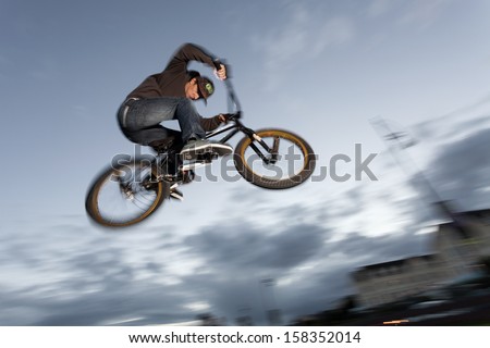 Young man performs BMX stunts during sunset at the street. Blurred motion.