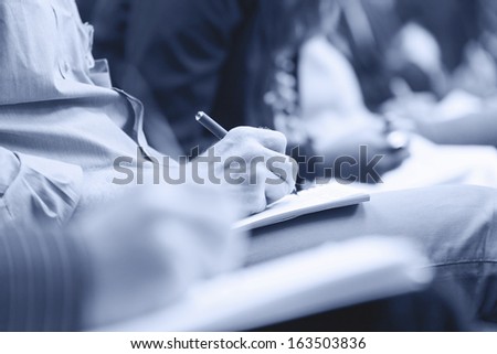 Close-up of Hands holding pens and making notes at the conference. Monochromatic