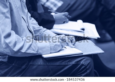 Close-up of Hands holding pens and making notes at the conference. Monochromatic