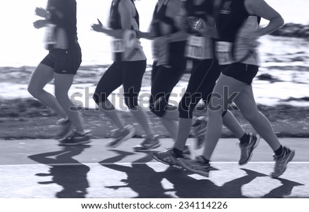 Group of woman compete in the race on coastal road. Blurred motion. Monochromatic