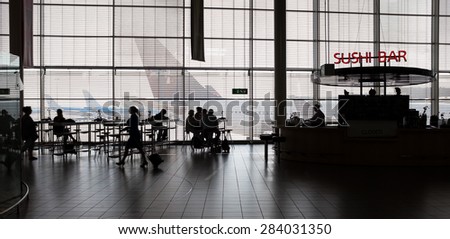 Airport interior with food bar and tourists.