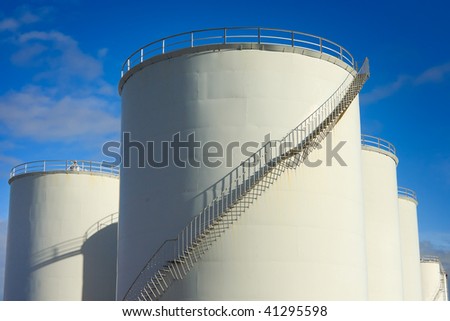 industrial metal white fuel tanks with stairs and blue sky