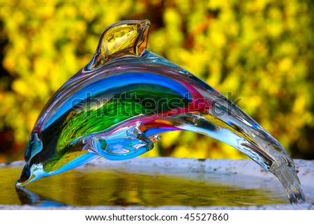crystal transparent dolphin sculpture on yellow-green blured background