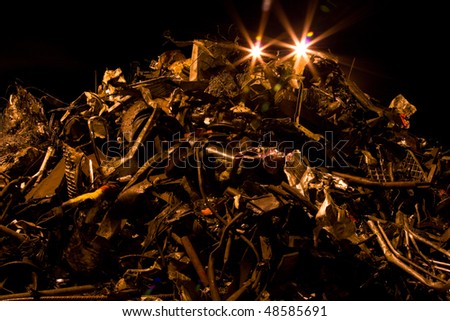 heap of rusty metal scrap and lights at night