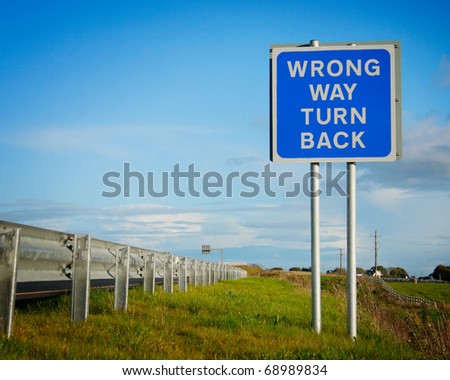 road  sign \' Wrong Way\' and blue sky with clouds