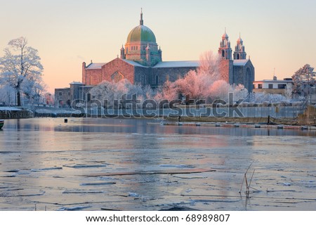 Galway Cathedral in First sunlights and Corrib river covered by ice at cold winter morning