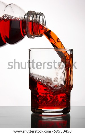 blackcurrant juice pouring into glass, close up on white background