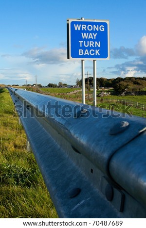 road sign \' Wrong Way\' and blue sky with clouds