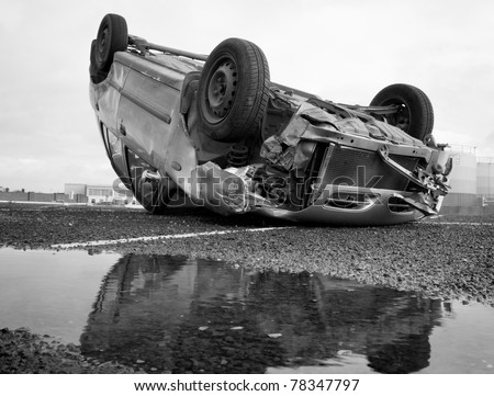 car turned upside-down after road collision and reflection in the water