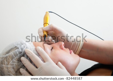 Cosmetologist making permanent makeup on woman\'s face