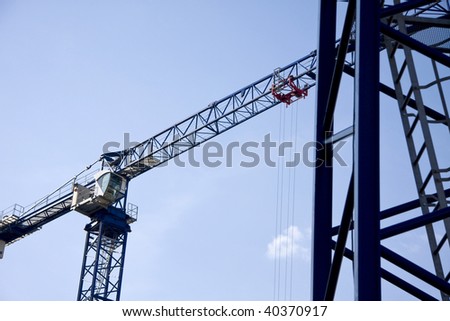 Two blue cranes on construction site.