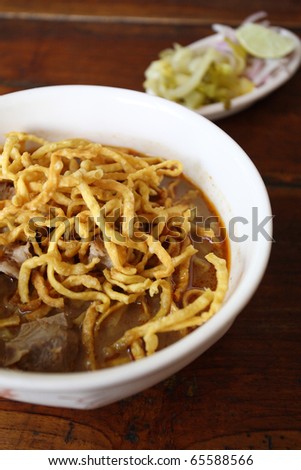 thai food Khao soy a famous northern noodle dish in beef curry with wood background