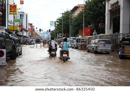 CHIANGMAI , THAILAND - SEPTEMBER 28: Thai monsoon People on motorcycle drive through flooded streets on September 28, 2011 in Chang Karn , Muang , Chiangmai , Thailand.