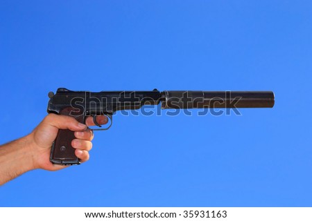 Pistol in a hand on a background blue sky. Automatic pistol of Stechkin was produced in a Soviet union. It one of the best auto pistols.