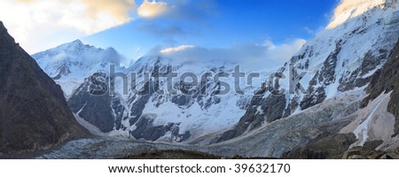 covered with snow and ice peaks of high mountains lit by the rays of the rising sun