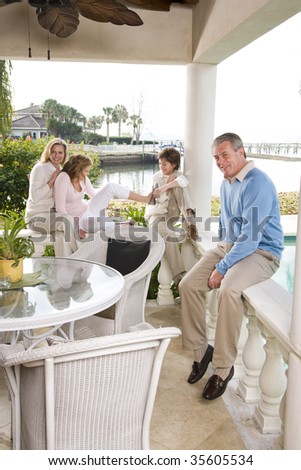 Portrait of family on vacation relaxing on terrace with siblings interacting