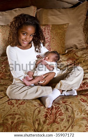 Ten year old girl holding newborn baby brother