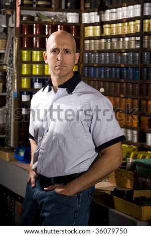 Portrait of mid adult man standing in front of colored inks in print shop
