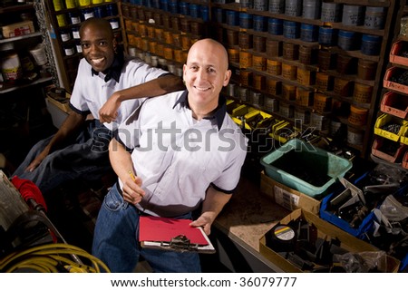 Male coworkers working in front of colored inks in print shop
