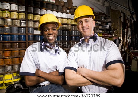 Male coworkers by shelves of colored inks in print shop