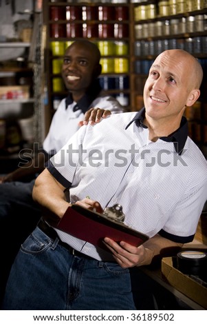 Coworkers in printing shop by shelves with inks